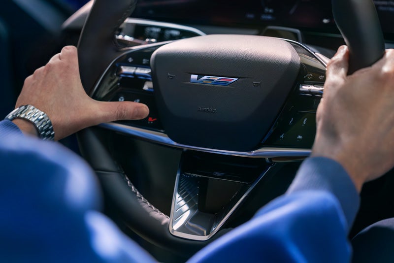 Close-up of a Man About to Press the V-Button on the 2026 OPTIQ-V Steering Wheel | Schepel Cadillac in Merrillville IN