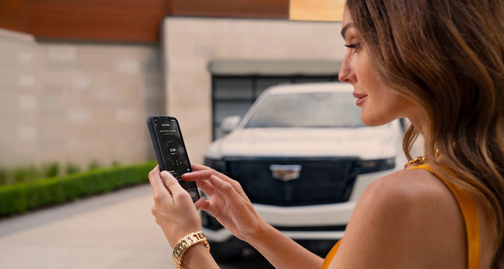 lady checking her mobile with a Cadillac vehicle background | Schepel Cadillac in Merrillville IN